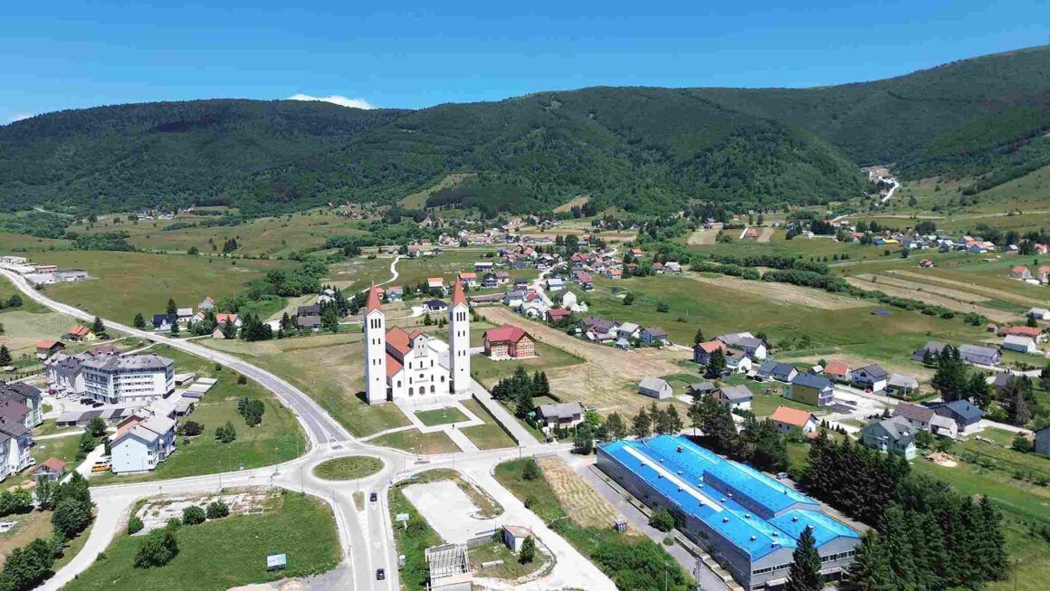 Pogled iz vazduha na Kupres, crkvu, naselje, puteve, polja i okolna brda.
